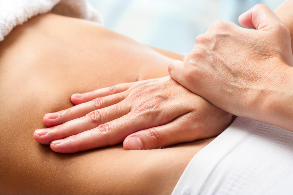 Hand auf dem Rücken eines Patienten, der eine osteopatische Behandlung erhält.